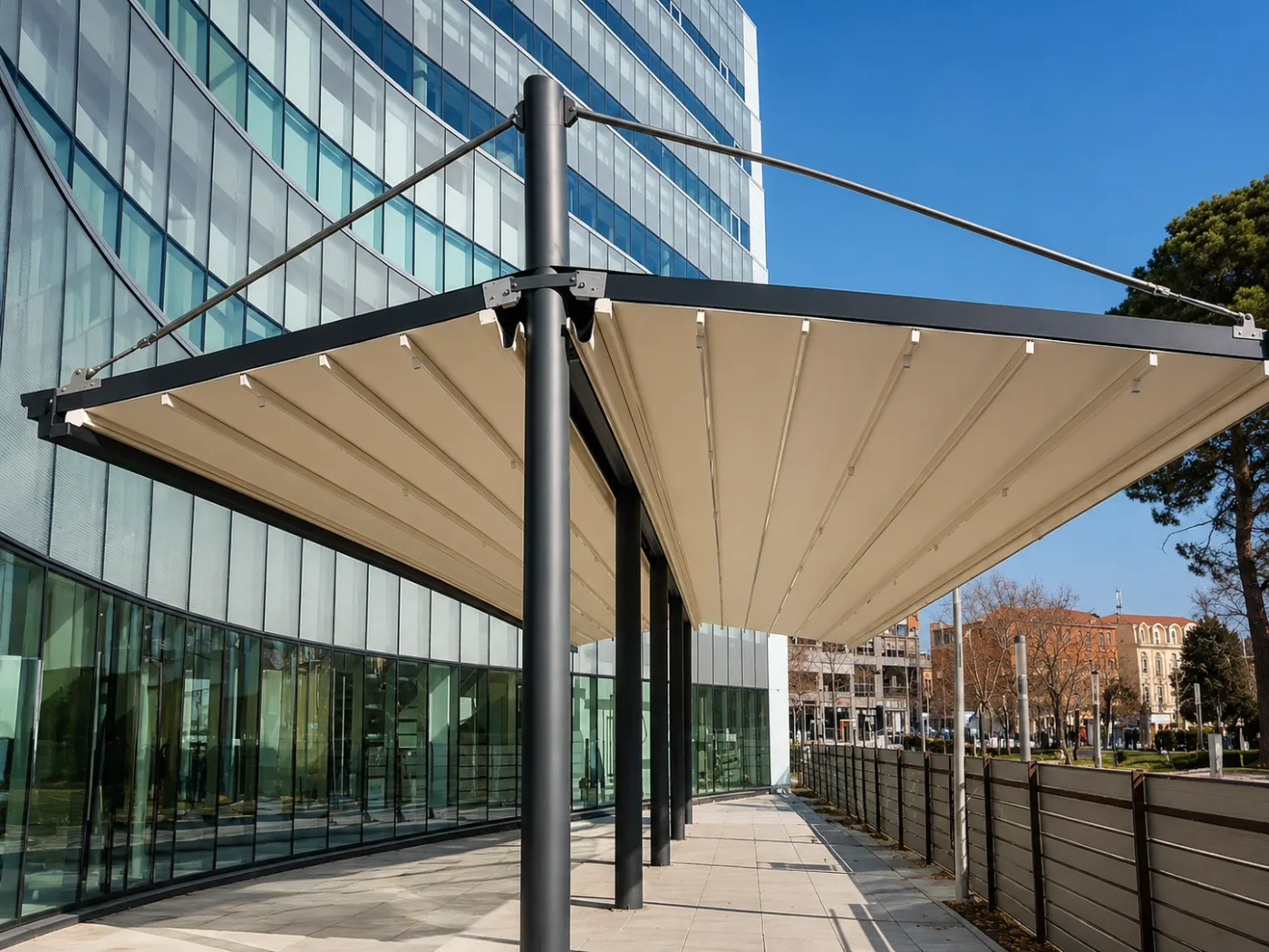 Freistehende Pergola-Markise mit beigem Tuch vor einer geschwungenen Glasfassade eines Bürogebäudes